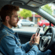 Jeune homme en voiture regardant son smartphone pour l'assurance