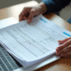 Mains tenant un tas de papiers officiels dont une carte grise française